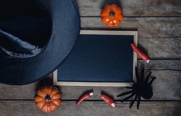 Halloween background with Pumpkins, Witch hat, spider, fingers and chalkboard 