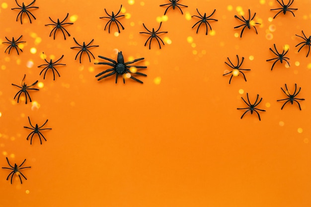 Halloween background with spiders on the bright orange backdrop. Top view, copy space for text
