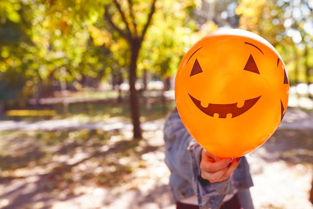 Palloncino di halloween con la faccia di zucca in mano