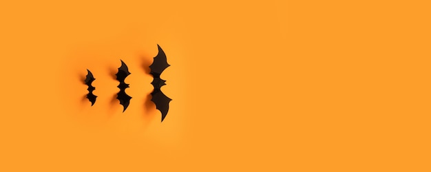 Halloween banner with black bats on an orange surface, top view