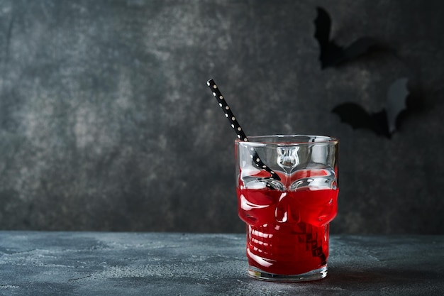 Halloween bloedige cocktail Bloedige rode cocktail glazen beker voor Halloween en fles vorm schedel op donkere achtergronden Halloween feest met snoep ogen vleermuizen spinnen Dia de los muertos Clousup