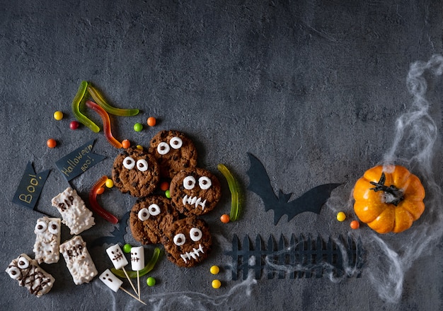 Halloween candy bar funny monsters made of biscuits with chocolate and ghosts marshmallow close-up on the table. Halloween party decoration. Trick or treat concept.