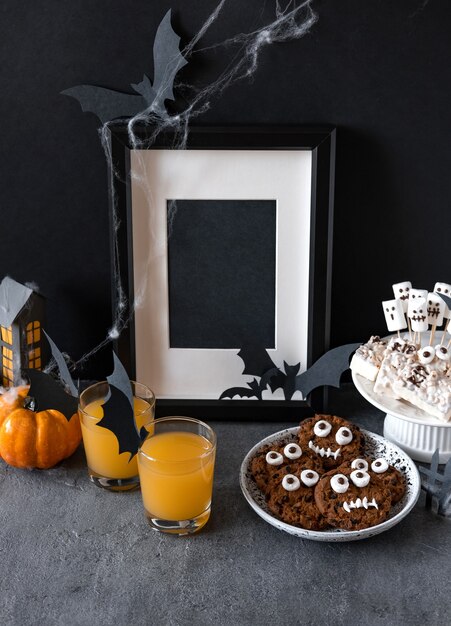 Halloween candy bar: funny monsters made of biscuits with chocolate and gummy worms, ghosts marshmelow close-up on the table