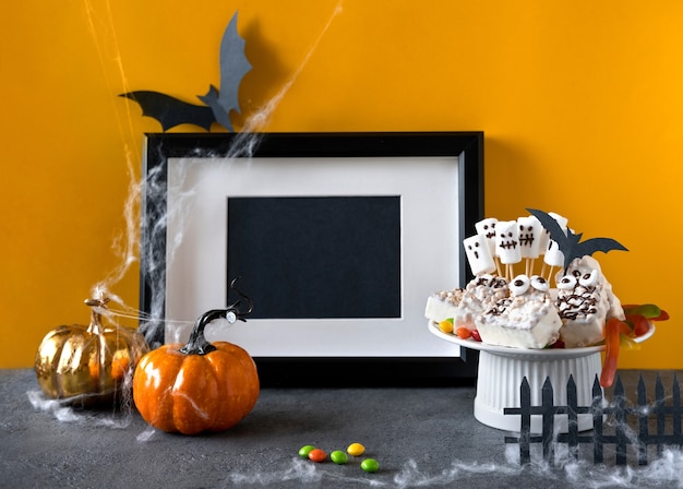 Halloween candy bar: grappige monsters gemaakt van koekjes met chocolade en gummy wormen, spoken marshmelow close-up op tafel