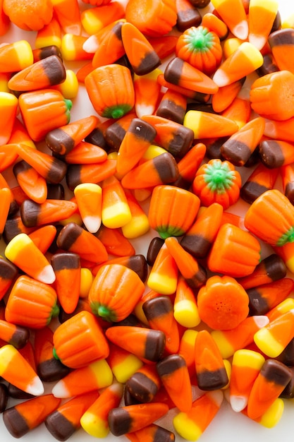 Halloween candy-corn and pumpkins in a pile.