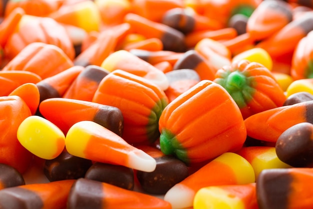 Halloween candy-corn and pumpkins in a pile.