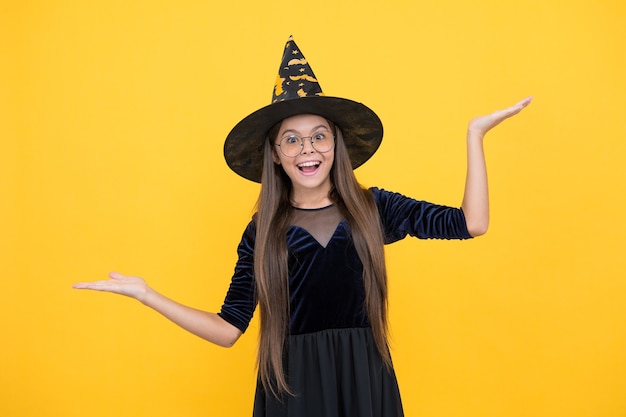 魔女の帽子と眼鏡をかけたハロウィーンの子供は、魔法使いの学校の生徒、幸せなハロウィーンの休日のように見えます。