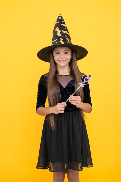 Хэллоуин ребенок в шляпе ведьмы держит волшебную палочку для колдовства счастливого хэллоуина