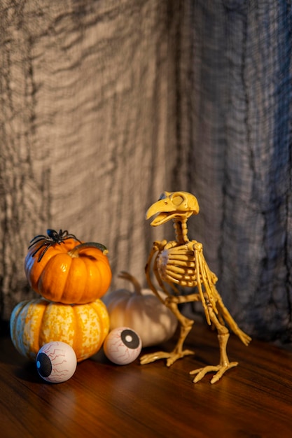 Halloween-compositie met minipompoenen, eng glas wijnstok met oogbollen naast vogelskelet