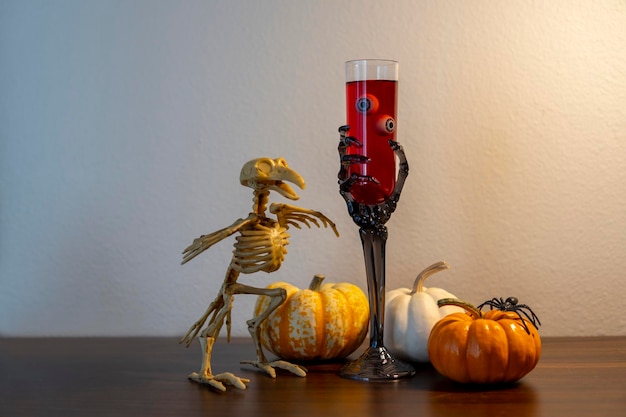 Halloween-compositie met minipompoenen, eng glas wijnstok met oogbollen naast vogelskelet