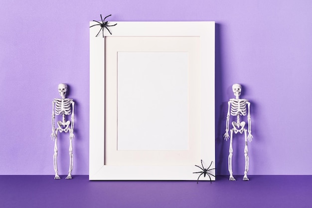 Halloween composition with frame and skeletons on table wall\
background greeting card template