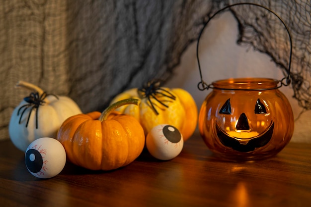 Halloween composition with mini pumpkins, with eyeballs next to Jack o lantern candlestick