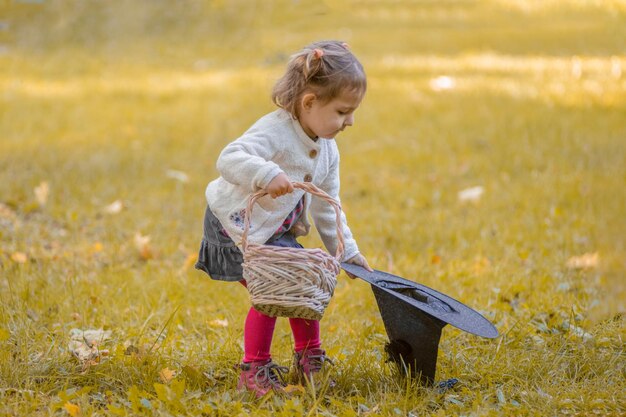 Halloween concept cute little girl playing with witch hat in autumn park