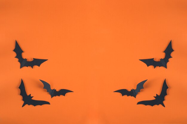 Halloween-concept en papieren versieringen. vleermuizen gesneden uit zwart papier op een oranje achtergrond. Papier gesneden stijl. Kopieerruimte bovenaanzicht