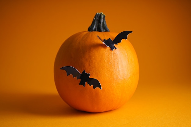 Concetto di halloween. zucca di halloween e pipistrelli su uno sfondo arancione.