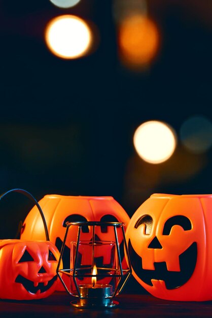 Концепция Хэллоуина Оранжевый пластиковый тыквенный фонарь на темном деревянном столе с размытым сверкающим светом на заднем плане трюк или угощение крупным планом