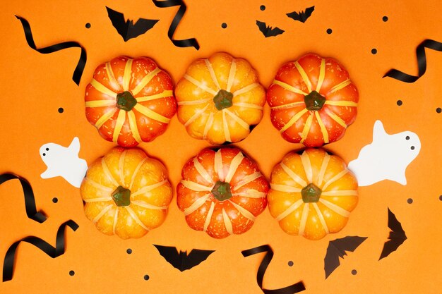 Halloween concept Scary smile pumpkins with bat and ghost arranged in center of orange background