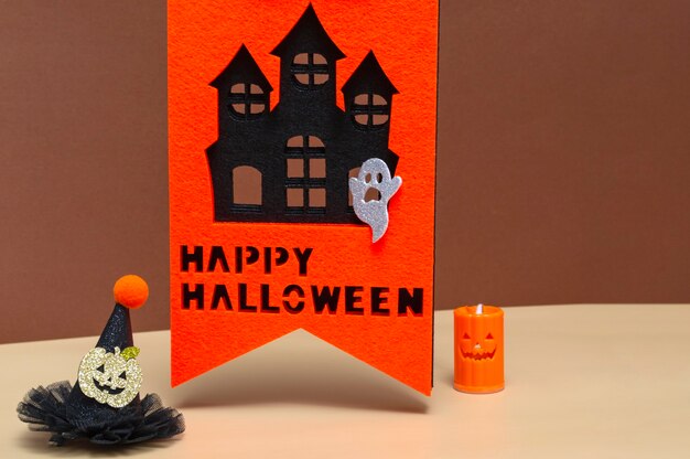 Halloween concept with haunted house, candle and witch hat on colored background. Halloween October 31