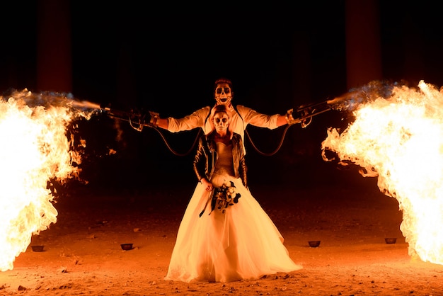 Halloween couple standing with flamethrower. 