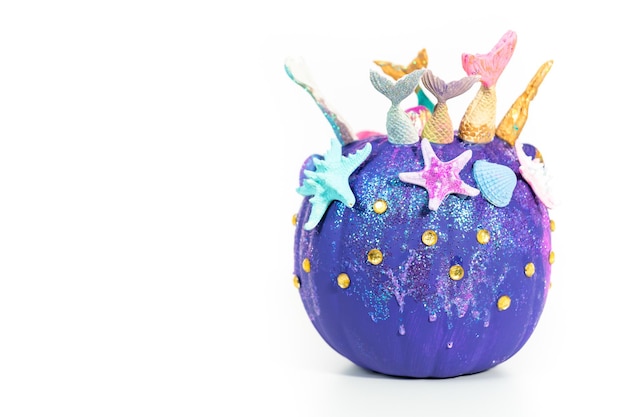 Halloween craft pumpkins decorated with mermaid tails, glitter, and sparkly rhinestones on a white background.