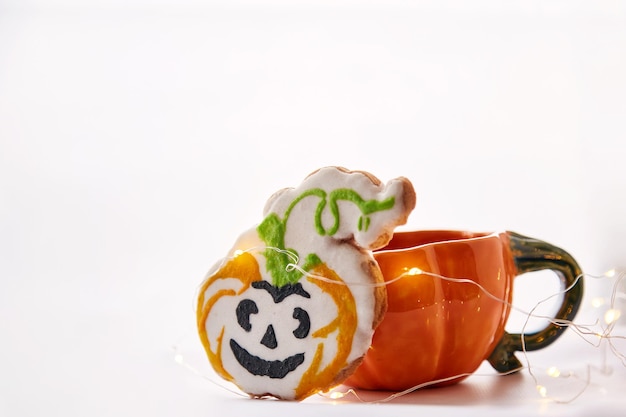 Halloween creative pumpkin cup and homemade cute cookies in shape of cute pumpkins