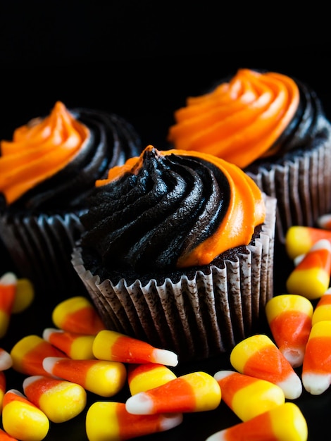 검은색과 주황색 소용돌이 모양의 아이싱으로 장식된 할로윈 컵케이크.