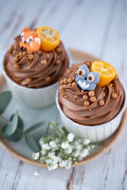 Halloween cupcakes with chocolate and pumpkins on white wooden background