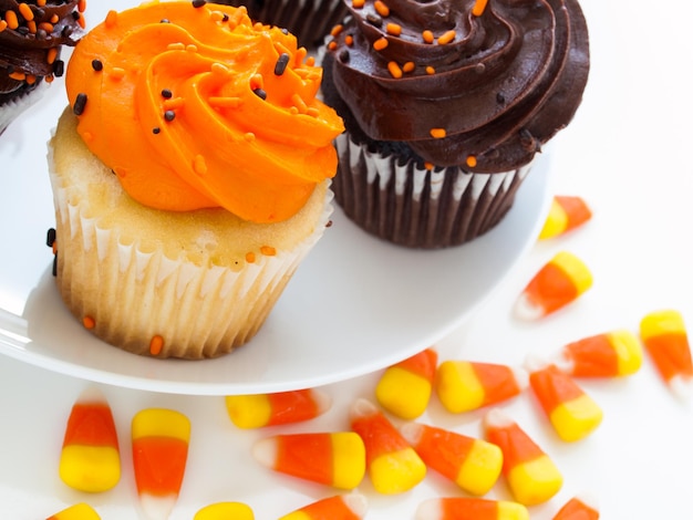 Halloween cupcakes with orange and black icing on white plate.