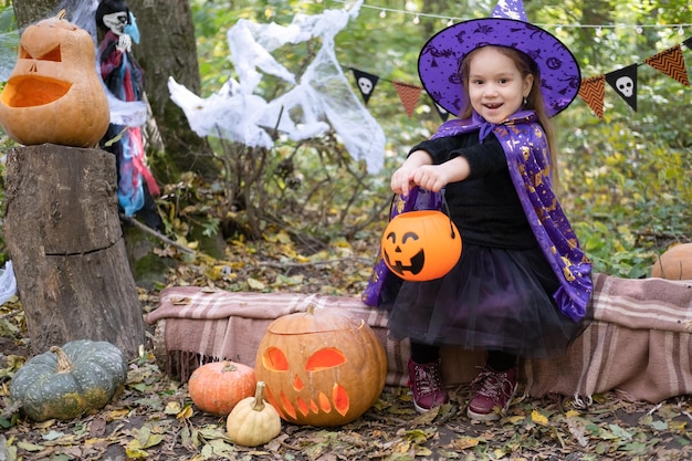 ハロウィン。屋外で楽しんでいるジャック o ランタンと魔女の衣装でかわいい女の子