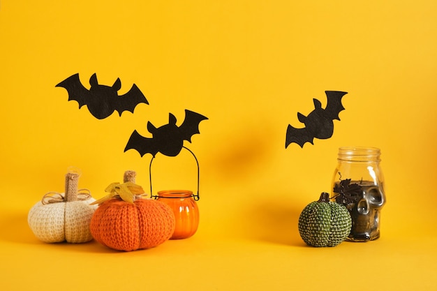 Halloween decor on a bright yellow background candles felt bats knitted and fabric homemade pumpkins