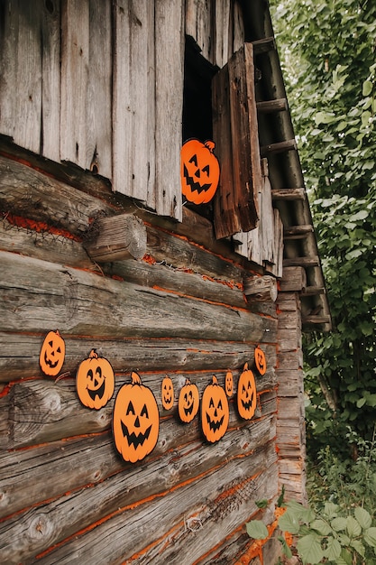 Halloween decor outdoors. Paper pumpkins on wooden building of the bathhouse in village.