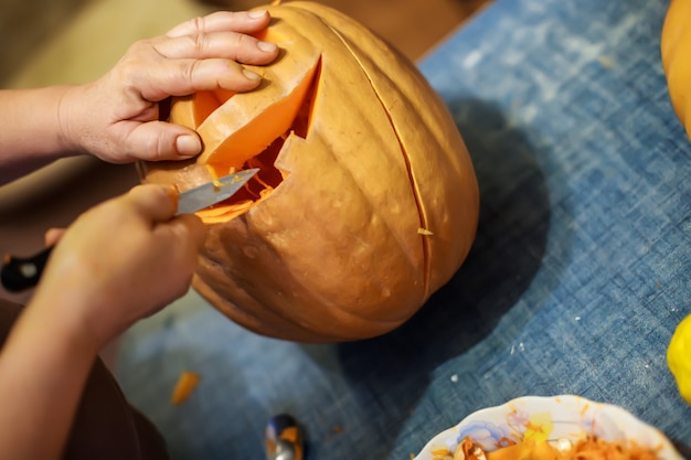 Halloween-decoratie en feestdagen close-up van vrouw met mes snijdende pompoen of jackolant