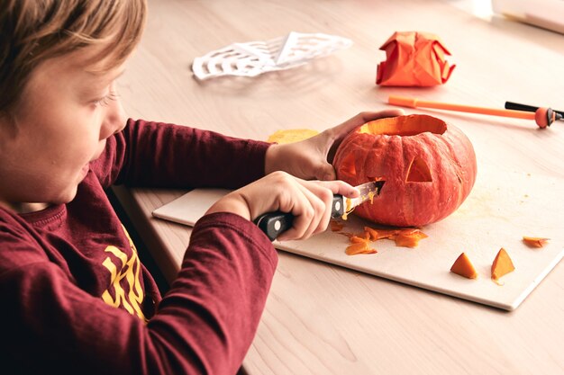 Halloween-, decoratie- en vakantie-ideeën - close-up van een kind met een pompoen of jack-o-lantern. 6 jaar jongen heeft een leuke activiteit voor het gezin. Moeder brengt samen tijd door met zoon