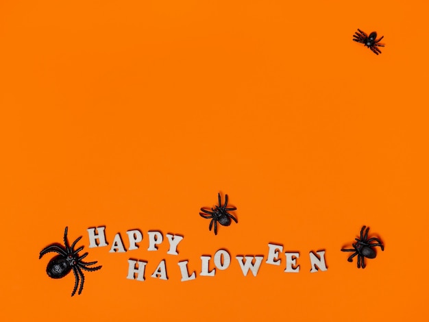 Halloween-decoraties op een oranje achtergrond met de inscriptie happy Halloween en spiders