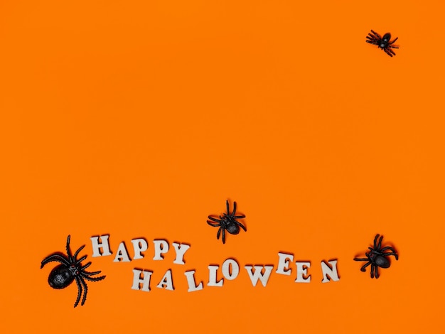 Halloween-decoraties op een oranje achtergrond met de inscriptie happy halloween en spiders