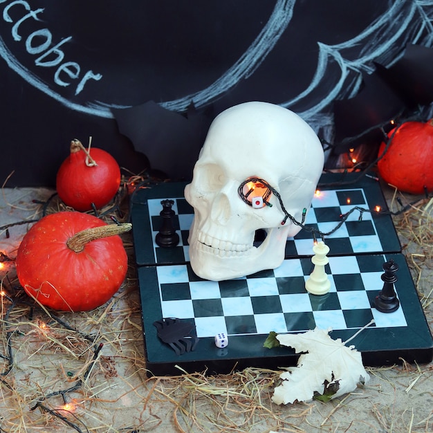 Halloween decoraties schedel op een schaakbord herfstbladeren en verlichting zwarte achtergrond