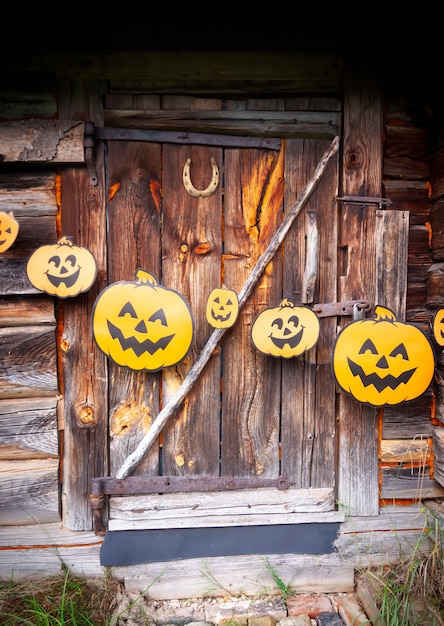 Halloween decoration outdoors. Paper garland with cute pumpkins hanging on the wooden wall of the old bathhouse building in village.