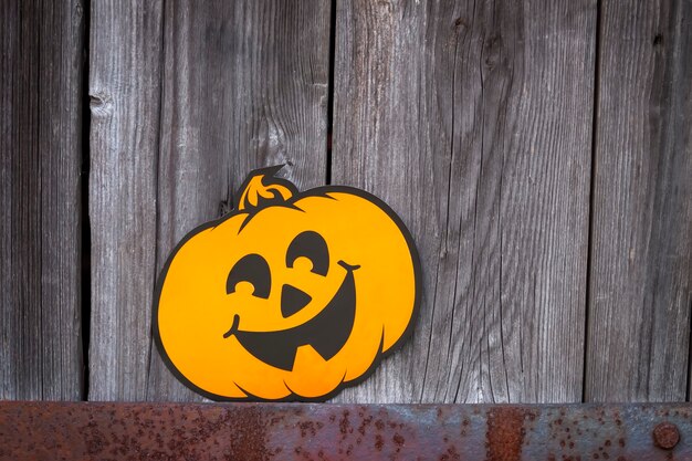 Halloween decoration outdoors. Paper garland with cute pumpkins hanging on the wooden wall of the old bathhouse building in village.