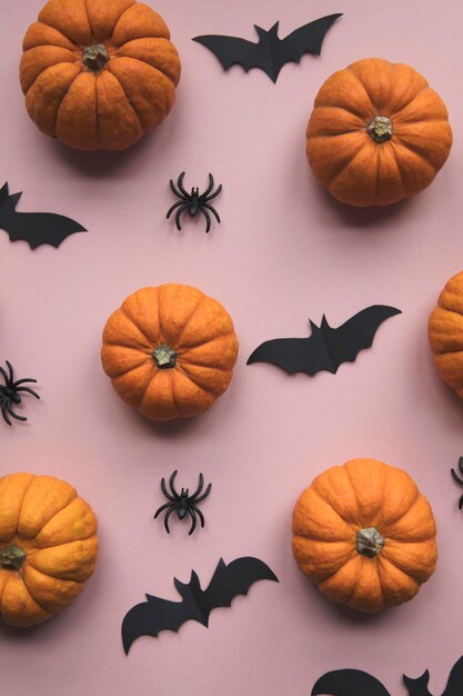 Halloween decorations on pastel pink background flat lay pumpkins spiders and bats