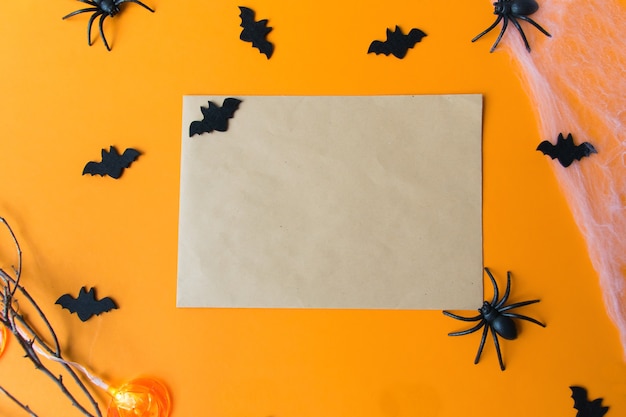 Halloween decorations, pumpkins, bats, web, bugs on orange background. Halloween party greeting card with copy space. Flat lay, top view.