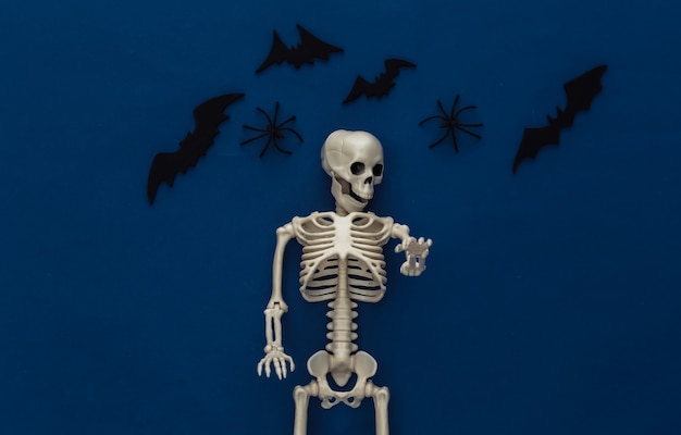 Halloween, decorazioni e concetto spaventoso. scheletro e ragni, pipistrelli neri sorvolano il classico blu scuro