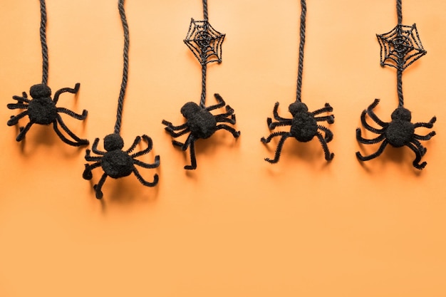 Halloween decorations with black spiders on orange background Flat lay top view copy space