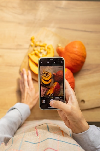 女性がスマートフォンのソーシャルメディアでオレンジ色のカボチャの写真を撮るハロウィーンの装飾