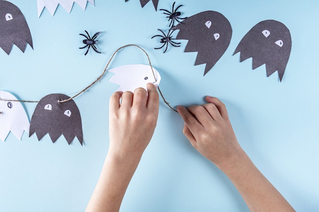 Halloween DIY en kinderen creativiteit. Stapsgewijze instructies om een krans van geesten van papier te maken