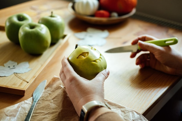 Halloween diy fruit ideeën vrouwelijke handen snijden halloween groene appel met griezelig gesneden gezicht aan