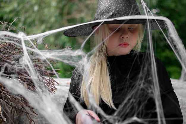Halloween en kinderen. Meisje in een zwarte hoed met spinnen en spinnenwebben, portret