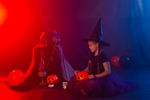 Halloween en vieringsconcept Kindmeisje in heksenkostuum met Halloween-pompoen die met hond jack russell terrier spelen
