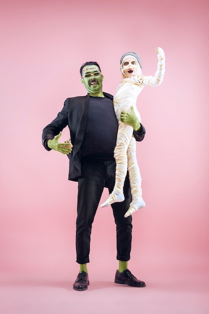 Foto famiglia di halloween. felice padre e bambini ragazza in costume di halloween e trucco. tema sanguinante: le facce del maniaco pazzo su sfondo rosa dello studio