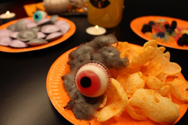 Foto halloween feest bord met snoep snoep en snacks zwarte katoen wolk chips en jelly bean oog