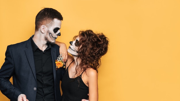 Halloween-feest. Een studio-opname van een jong stel in feestelijke Halloween-kostuums en met make-up op hun gezicht. Een plek voor uw tekst, reclame.